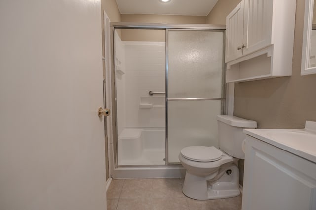 bathroom featuring a shower with door, vanity, tile patterned floors, and toilet