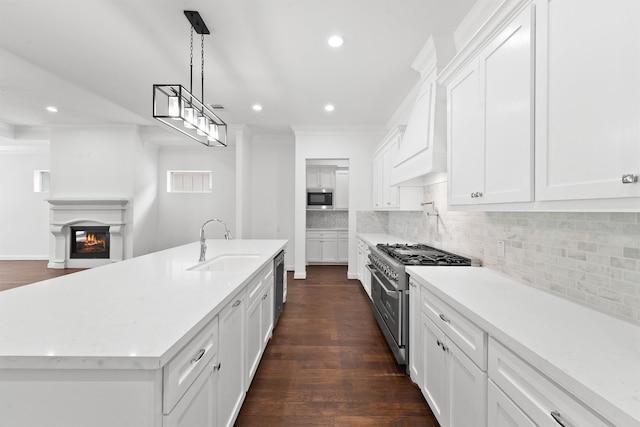 kitchen with stainless steel appliances, tasteful backsplash, ornamental molding, a glass covered fireplace, and a sink