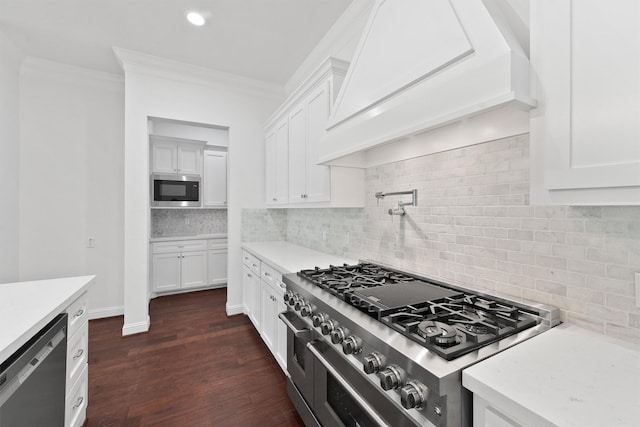 kitchen with stainless steel appliances, dark wood-type flooring, white cabinets, ornamental molding, and tasteful backsplash