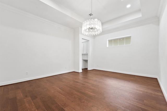 unfurnished room featuring dark wood-style floors, a tray ceiling, and baseboards