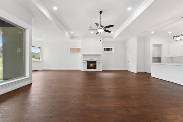 unfurnished living room with visible vents, dark wood-style flooring, a lit fireplace, a tray ceiling, and crown molding