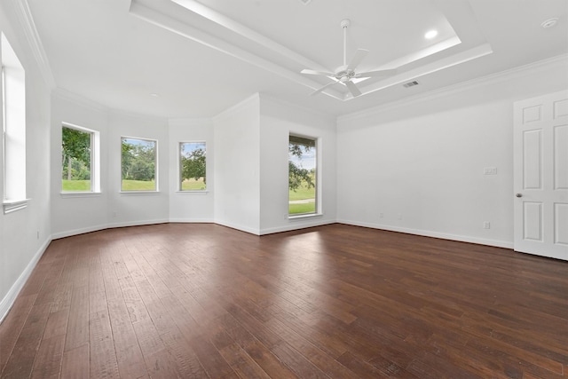 empty room with dark wood-style floors, a raised ceiling, visible vents, and a healthy amount of sunlight