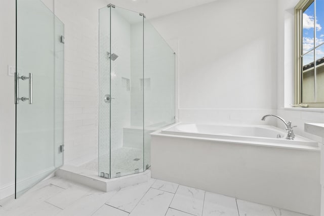 bathroom featuring marble finish floor, a garden tub, and a stall shower