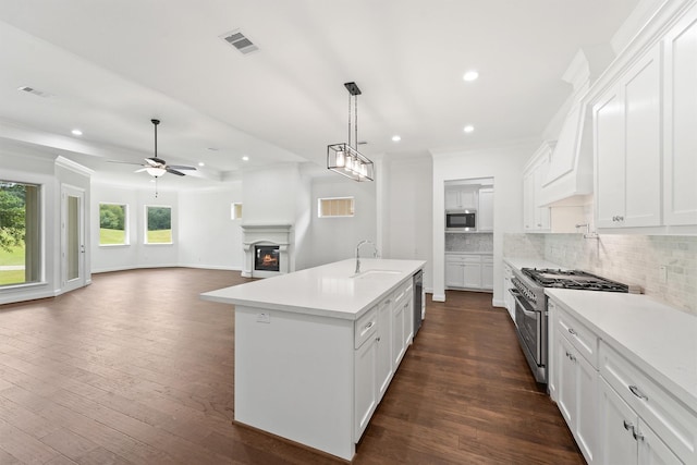 kitchen with a sink, visible vents, appliances with stainless steel finishes, decorative backsplash, and dark wood-style floors