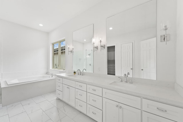 full bathroom with marble finish floor, double vanity, a sink, and a bath