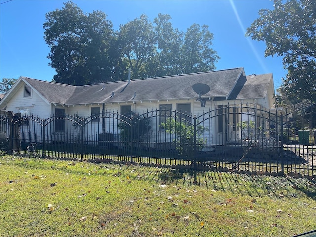 view of front of property with fence private yard, roof with shingles, and a front yard