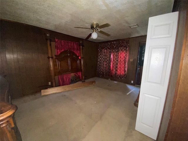 unfurnished bedroom with ceiling fan, concrete floors, and wooden walls