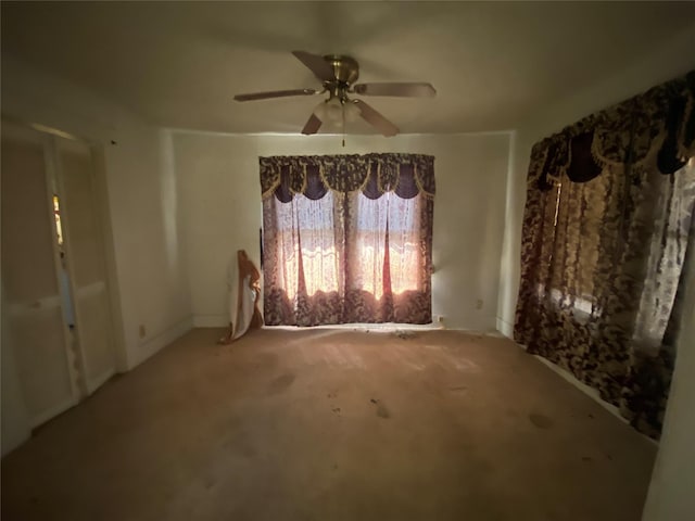 carpeted spare room with a ceiling fan and baseboards