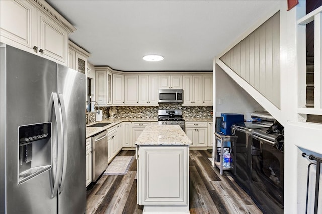 kitchen with stainless steel appliances, dark hardwood / wood-style flooring, a center island, light stone countertops, and sink