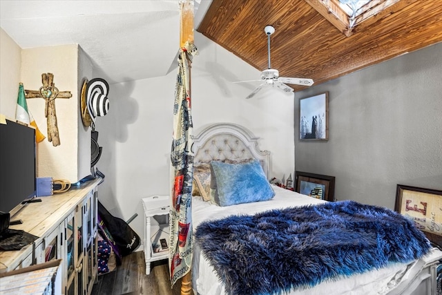 bedroom featuring dark wood-type flooring, a skylight, ceiling fan, and wood ceiling