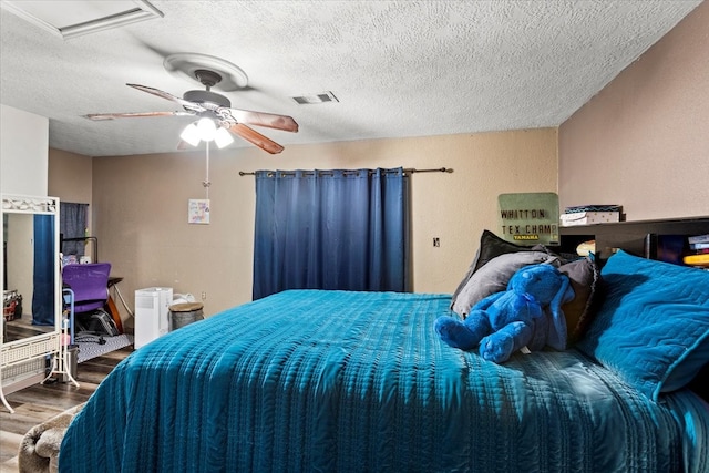 bedroom featuring a textured ceiling, wood-type flooring, and ceiling fan