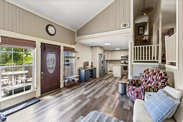 foyer with wooden walls, vaulted ceiling, dark hardwood / wood-style floors, ceiling fan, and ornamental molding