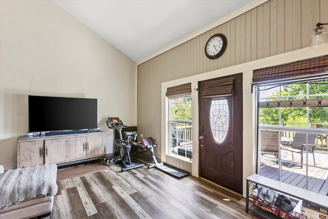 entrance foyer with wood walls, hardwood / wood-style floors, and high vaulted ceiling