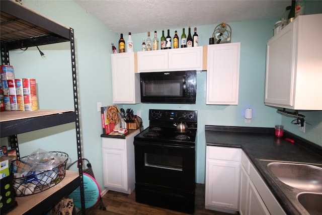 kitchen with a textured ceiling, white cabinets, black appliances, and dark hardwood / wood-style floors