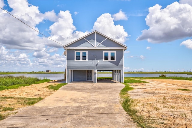 beach home with a carport, concrete driveway, and a water view