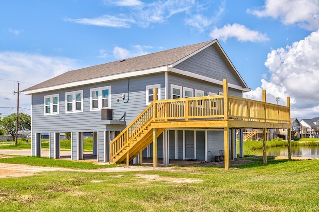 back of house featuring stairway, a yard, a deck with water view, and roof with shingles