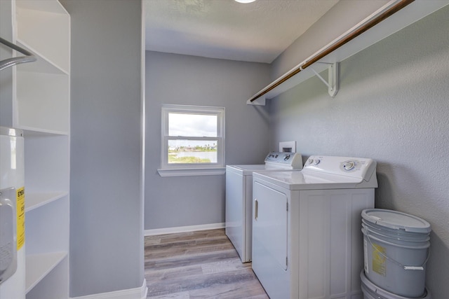 laundry area with washer and dryer, a textured ceiling, light wood finished floors, baseboards, and laundry area