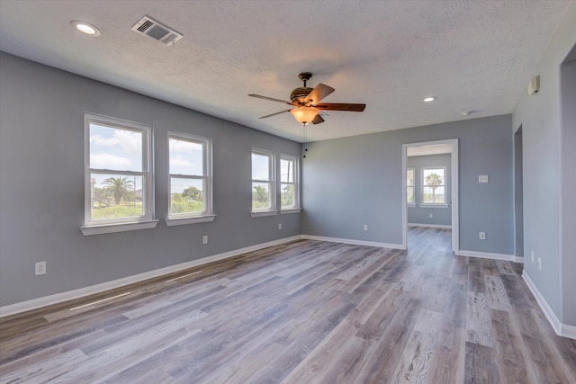 spare room featuring a wealth of natural light, visible vents, baseboards, and wood finished floors