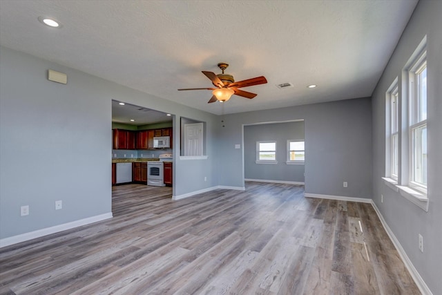 unfurnished living room featuring visible vents, baseboards, ceiling fan, and light wood finished floors