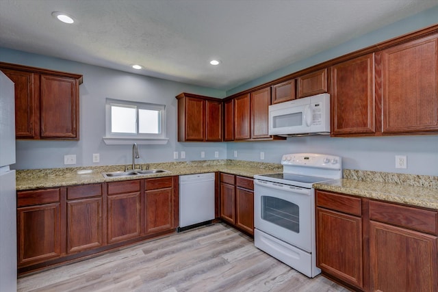 kitchen featuring a sink, recessed lighting, white appliances, light wood finished floors, and light stone countertops