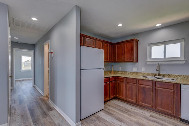 kitchen featuring visible vents, white appliances, light wood-style floors, and a sink