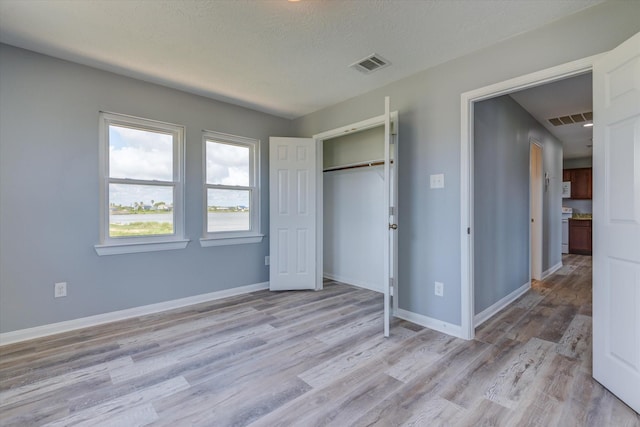 unfurnished bedroom featuring visible vents, light wood-style flooring, and baseboards