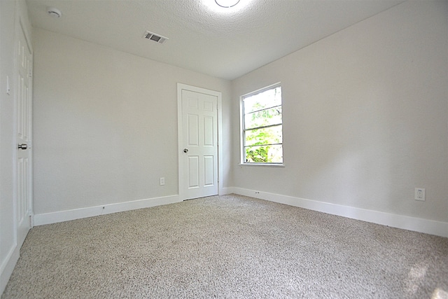 carpeted empty room with a textured ceiling