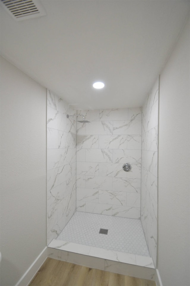 bathroom with hardwood / wood-style floors and tiled shower