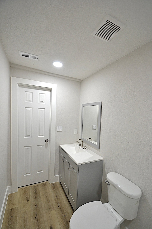 bathroom with hardwood / wood-style floors, toilet, and vanity