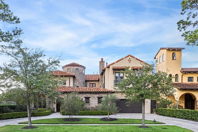 mediterranean / spanish-style home with a garage and a front lawn