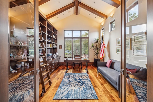 living area featuring beamed ceiling, high vaulted ceiling, and light hardwood / wood-style flooring