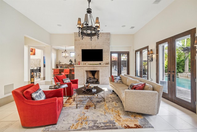 living room with a notable chandelier, a large fireplace, a wealth of natural light, and french doors