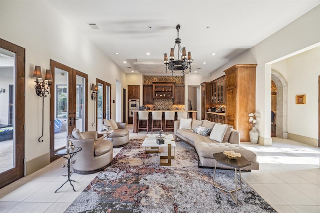 living room featuring an inviting chandelier, light tile patterned floors, and french doors