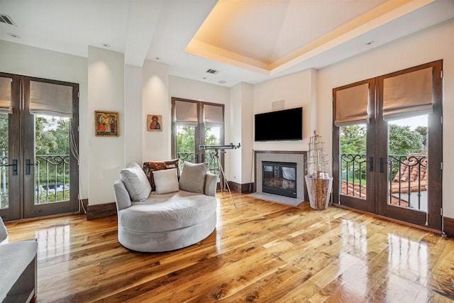 living room featuring light hardwood / wood-style floors, french doors, and a raised ceiling