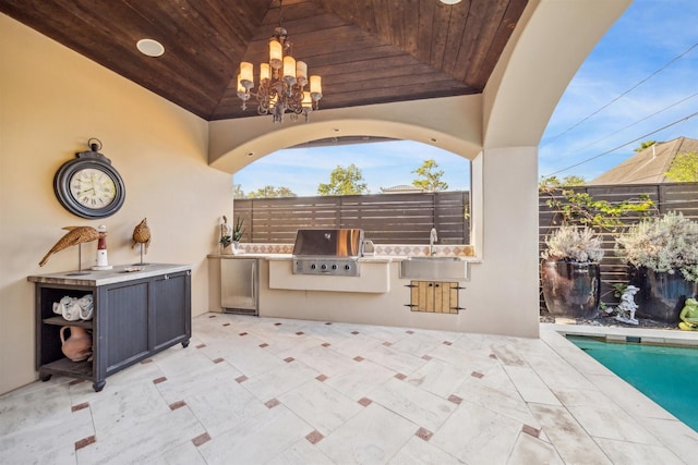 view of patio / terrace featuring a fenced in pool, an outdoor kitchen, and a grill