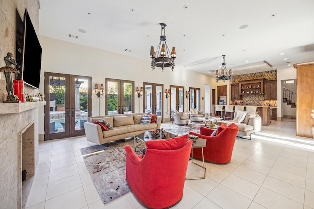 tiled living room with a fireplace, an inviting chandelier, and french doors