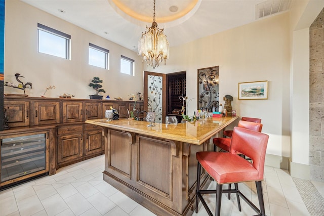 bar with pendant lighting, light tile patterned floors, a notable chandelier, and light stone countertops