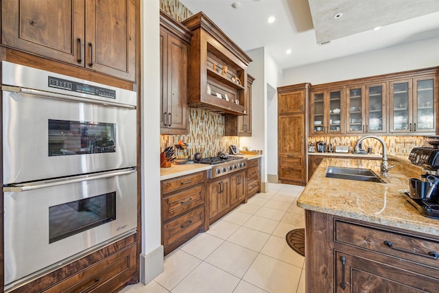 kitchen with sink, stainless steel appliances, light stone counters, light tile patterned flooring, and decorative backsplash