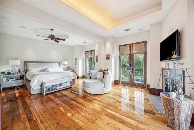 bedroom featuring hardwood / wood-style flooring, ceiling fan, a raised ceiling, and access to outside