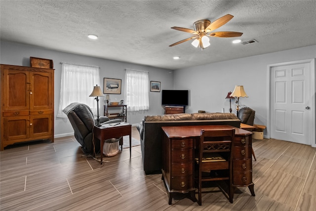 living room with a textured ceiling and ceiling fan