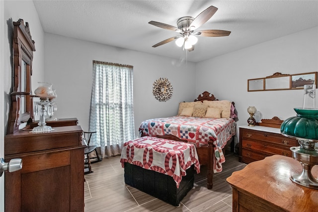 bedroom featuring ceiling fan, light wood-type flooring, and a textured ceiling