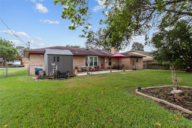 back of property with a lawn, a patio area, and a storage unit