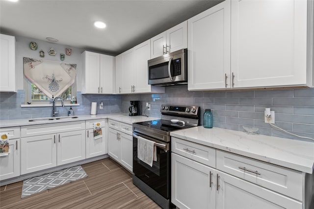 kitchen featuring decorative backsplash, appliances with stainless steel finishes, white cabinetry, and sink