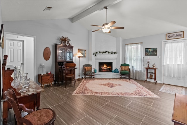 living room featuring a fireplace, lofted ceiling with beams, and ceiling fan