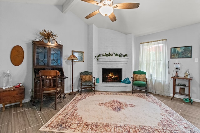 living area with vaulted ceiling with beams, ceiling fan, wood-type flooring, and a brick fireplace