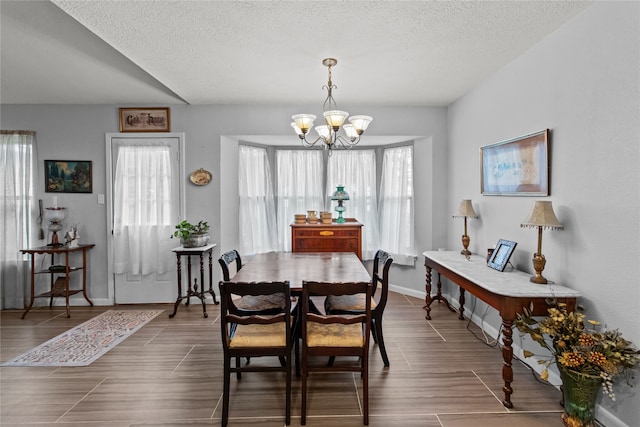 dining space with dark hardwood / wood-style floors, a textured ceiling, and a notable chandelier