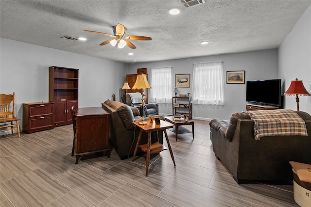 living room with a textured ceiling and ceiling fan