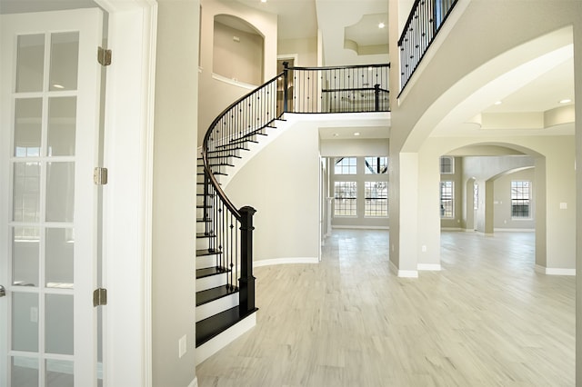 staircase with hardwood / wood-style floors, plenty of natural light, and a high ceiling