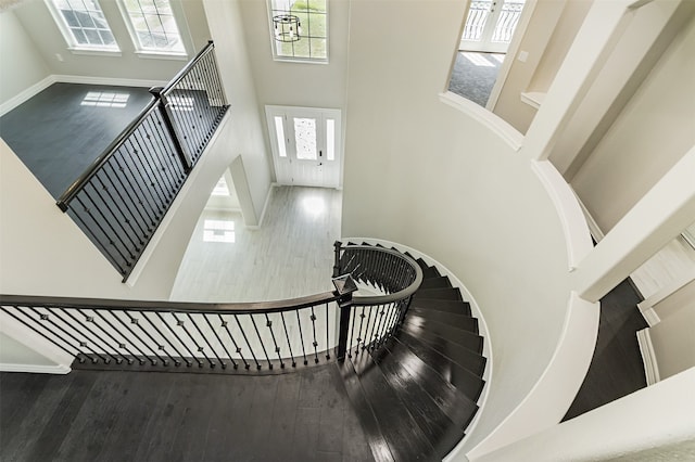 staircase featuring a high ceiling, hardwood / wood-style flooring, and a wealth of natural light