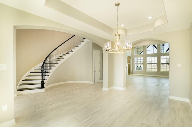 1714 Mackey Dr, Dickinson, TX 77539 - interior space featuring a chandelier, arched walkways, a tray ceiling, stairway, and light wood-style flooring
